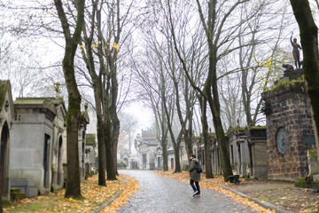 Obraz premium Tourist walking in pere lachaise cemetery on a foggy autumn day in paris