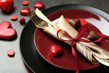Romantic place setting for Valentine's day. Tableware, cutlery and candies in shape of hearts on...