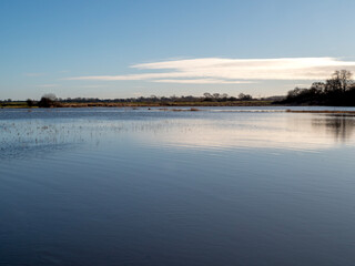 View over a calm lake with a clear blue sky and white cloud