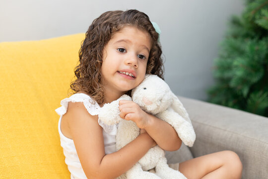 menina abra&ccedil;ada com urso de pel&uacute;cia sorrindo