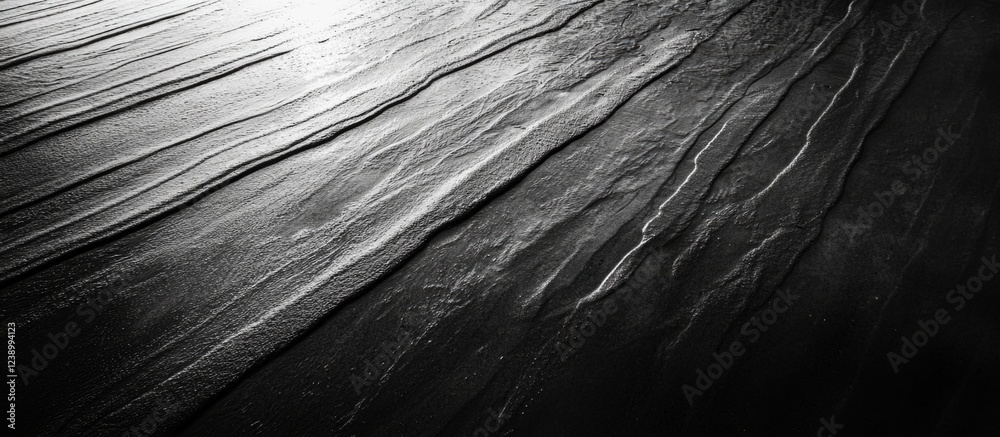 Poster black and white abstract texture of wet sand with smooth lines and patterns illuminated by light cop