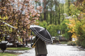 A small child of 5 years old with an umbrella in his hands during the spring rain. A spring break photo. A child under an umbrella.