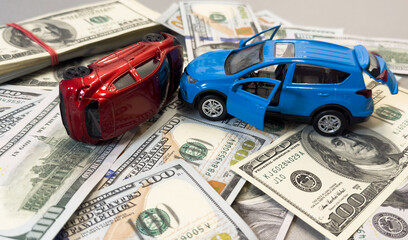 Toy cars in accident on a background of 100 dollar bills