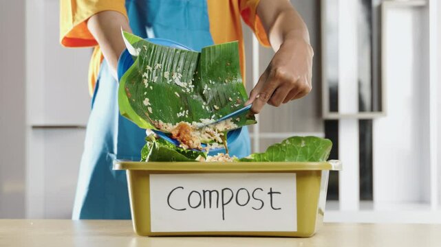 Recycling leftover food into compost at home. Close up of hands placing food waste into a compost bin for sustainable living. Organic waste, food scraps, compost bucket, recycling, eco-friendly