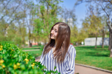 Obraz premium A beautiful girl in a checkered shirt walks in the park on a spring morning.