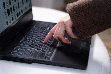 female hand presses a button on a laptop keyboard with one finger