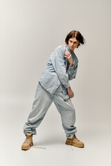 Fototapeta premium Confident young man showcases his fashion sense with a trendy denim ensemble and unique stance
