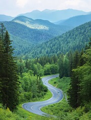 Fototapeta premium Winding road through lush green forest mountains with hazy blue peaks in the distance