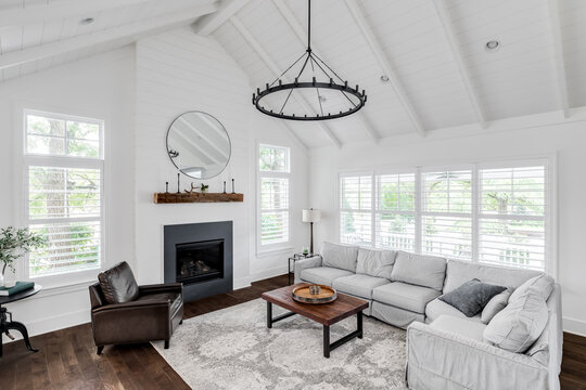 A modern farmhouse living room with shiplap, exposed white beams, a fireplace, and furniture on hardwood floors. No brands or labels.