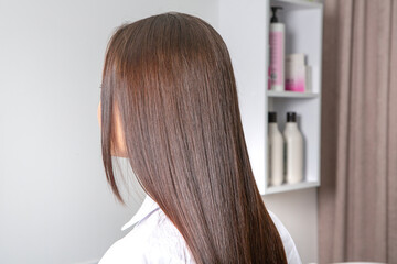 Naklejka premium woman combs her beautiful brunette hair at the beauty salon. Healthy hair