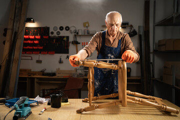 furniture restorer measuring chair leg in woodworking workshop