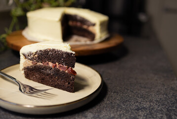 Slice of Cake on Plate. Blurred Whole Cake in Background, copy space