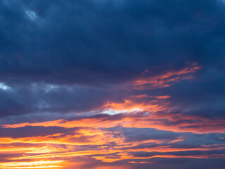 Dramatic clouds in orange and blue colors at sunset. Beautiful evening sky background