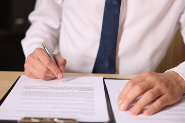 Man putting signature on document at table, closeup