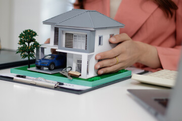 Young Asian woman in office, architecture, building, construction, real estate and property concept - close up of mobile phone, house model