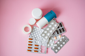 A large arrangement of various pills and bottles is thoughtfully displayed against a vibrant pink...