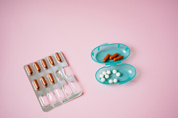 A vivid pink background serves as the setting for a blister pack filled with pills alongside a...