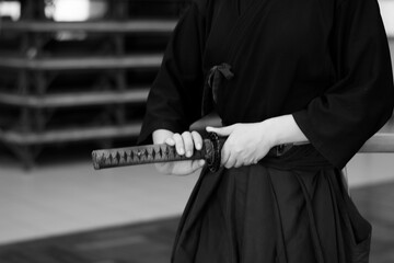 A fierce samurai grips a Japanese katana sword, practices Iaido in black and white. Shadows and...