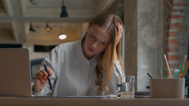 Stressed Caucasian office female worker woman student girl work reading documents writing report studying businesswoman business problem stack stats stress migraine headache overworked at workplace