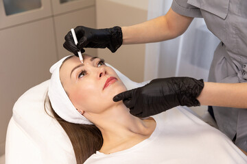 Close-up. Before the procedure for facial contouring or plastic surgery, the cosmetologist makes markings on the patient face. Time to prepare for a cosmetic procedure.