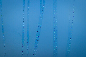 Close-up of blue-toned condensation on glass with visible streaks, creating a cool, abstract background with a fresh and clean atmosphere.