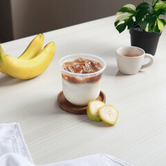 Enjoy a delightful yogurt dessert topped with iced coffee, accompanied by fresh bananas and a slice of green fruit on a playful wooden table