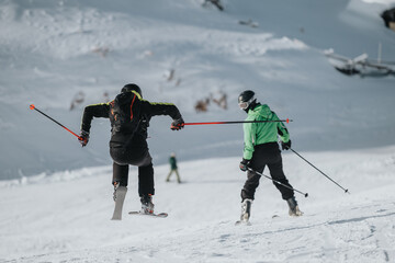 Ski enthusiasts in action during daytime on a snowy mountain, showcasing enthusiasm and skill.