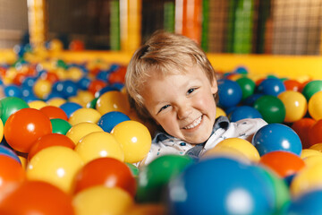Happy Little Boy Swimming in a Ball Pit Pool in Amusement Park. Kids Playing and Having Fun at Children Play Centre
