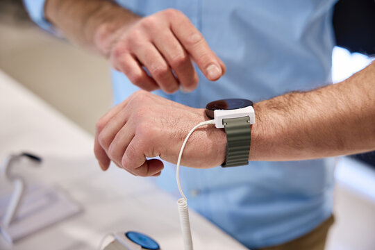 A person is testing a Smartwatch while using its Charging Cable inside a Technology Store