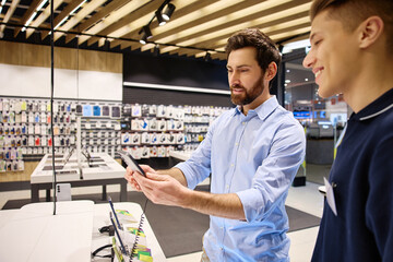 A friendly interaction occurs between a salesperson and a customer in a smartphone store