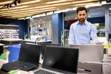 A Young Professional Enthusiastically Engaging with Laptops in a Modern Retail Store Environment