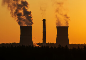 Power Plant with Dual Cooling Towers and Smokestack at Sunset Silhouette with Smoke