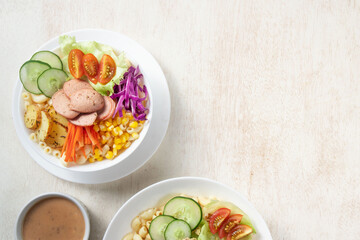 Vegetable salad, Colorful salad bowls filled with fresh vegetables, macaroni, and sliced meats are arranged on a rustic wooden surface alongside drinks