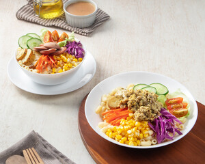 Two vibrant bowls filled with assorted Salad, vegetables, pasta, and fresh ingredients displayed on a wooden surface at a casual dining setting