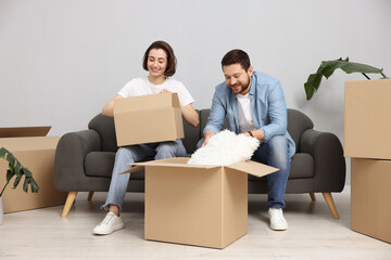 Moving day. Happy couple unpacking their belongings in new home