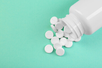 Bottle of antibiotic pills on turquoise background, top view. Space for text