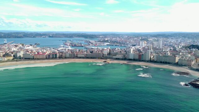 Beautiful panoramic aerial perspective of A Coruna city. Drone going backwards above the bay. Old historic center of the city and Port of A Coruna. Orzan Beach. Fanous travel destination in Galicia.