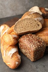 Different freshly baked bread loafs on grey table, closeup