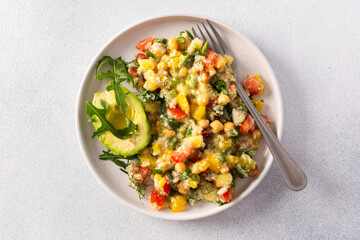 Enjoy a nutritious salad of boiled millet, chickpeas, fresh vegetables, and avocado, topped with olive oil, perfect for a wholesome vegetarian diet rich in vitamins and minerals