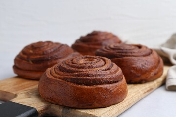 Delicious cinnamon roll buns on light table, closeup