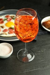 Tasty brunch. Aperol cocktail, delicious fried eggs with sausage served on black table, closeup