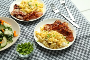 Tasty brunch. Delicious scrambled eggs, bacon and salad served on white table