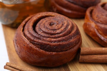 Delicious cinnamon rolls and sticks on white table, closeup