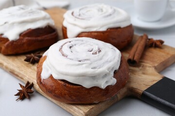 Tasty cinnamon rolls with cream and spices on white table, closeup