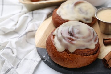 Tasty cinnamon rolls with cream and spices on table, closeup. Space for text