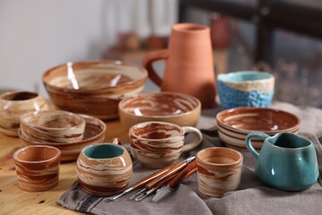 Different beautiful pottery and set of clay crafting tools on wooden table indoors, closeup