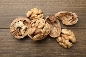 Fresh walnuts with shells on wooden table, flat lay