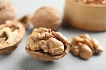 Fresh walnuts with shells on gray table, closeup