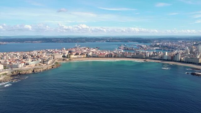 Bautiful panoramic aerial perspective of A Coruna city. Drone going backwards above the bay. Old historic center of the city and Port of A Coruna. Orzan Beach. Fanous travel destination in Galicia.
