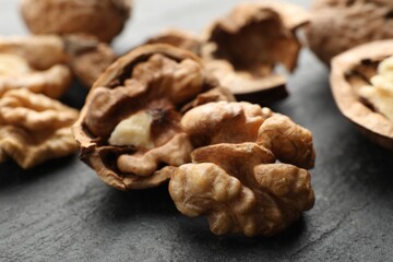 Fresh ripe walnuts and shells on black table, closeup